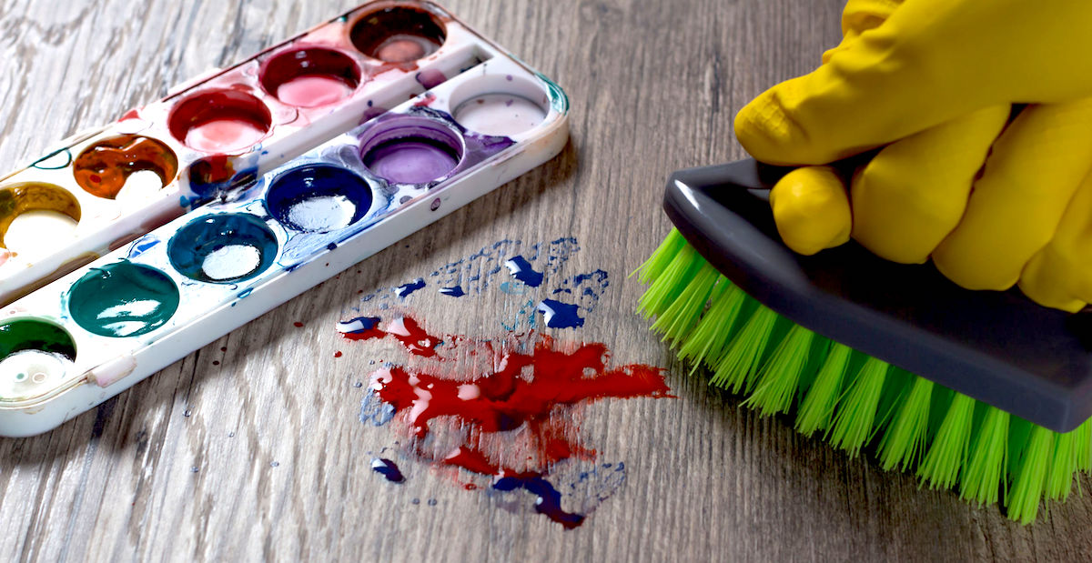 The woman brushing the stain from the paint. Clean up, wash. A mess. A gloved hand wipes the stain from the paints.The woman does the cleaning. Clean, house, housekeeper, cleanup and housework.