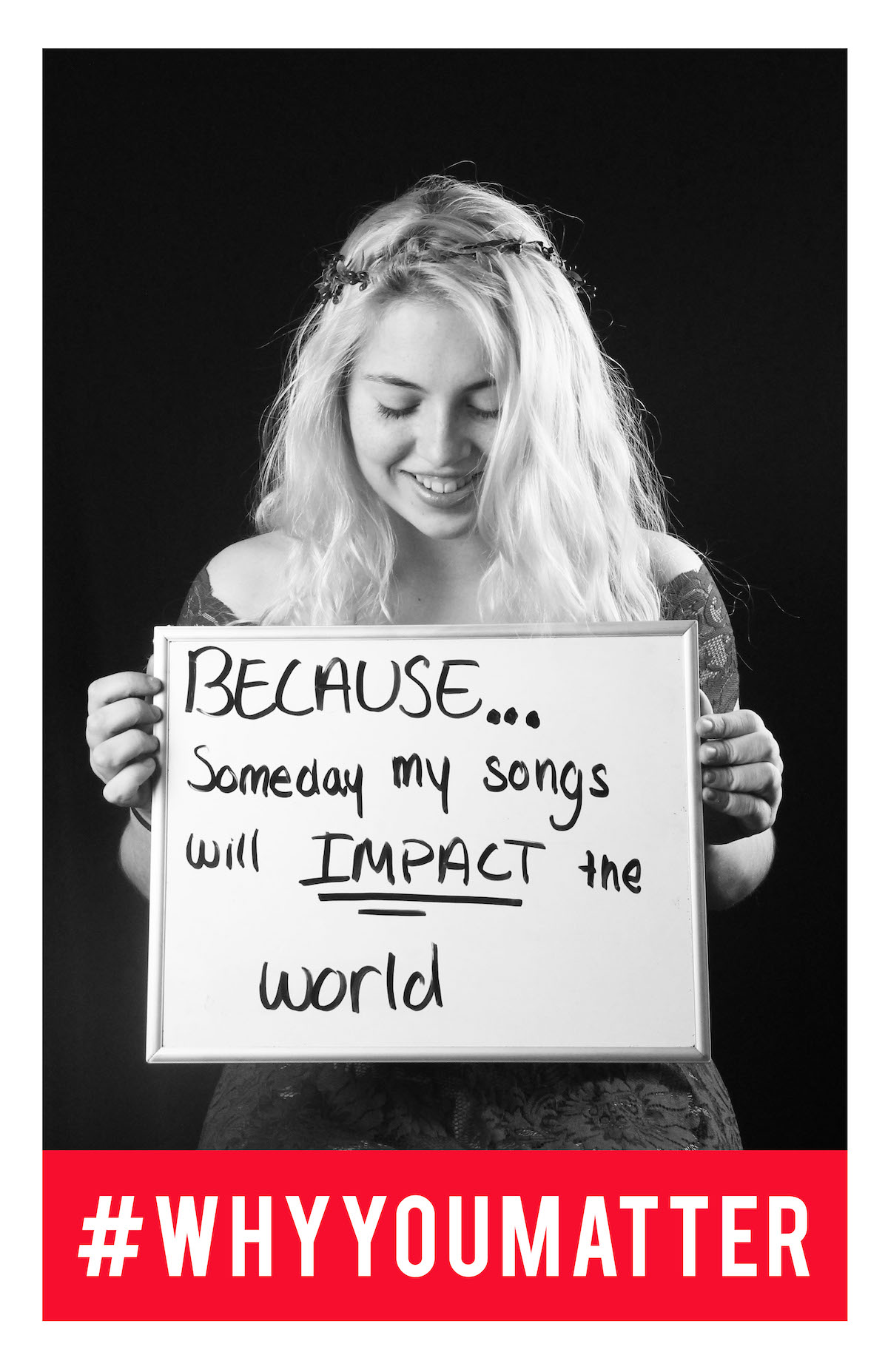 student holding sign that says 'because someday my songs will impact the world.'