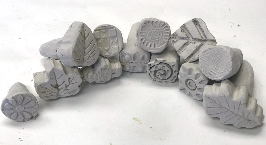curved row of hand carved texture stamps out of clay
