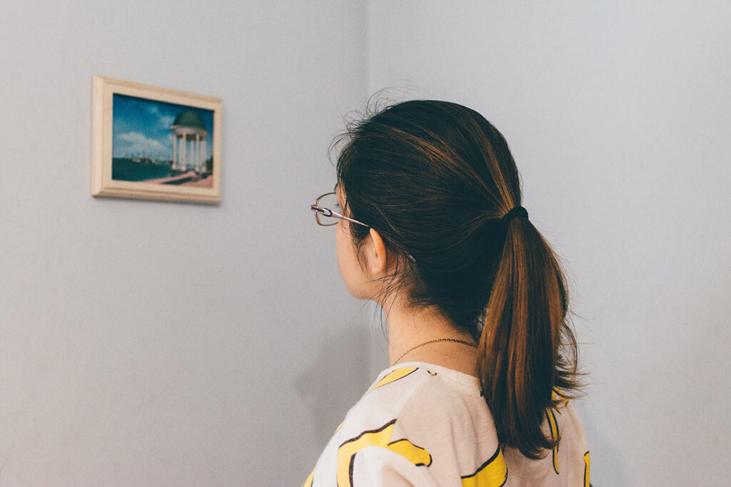 girl looking at small painting on wall