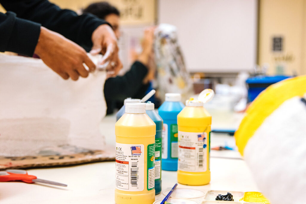 students working with paint bottles on table